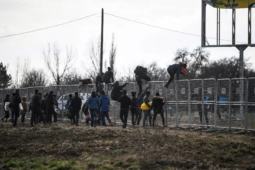 Migrants jump over fences erected by the Turkish army near the Pazarkule border gate in Edirne on March 4, 2020, during their journey to try to enter Europe.