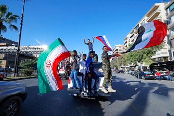 Syrian government supporters wave Syrian (R), Iranian (L), and Russian flags in Damascus, Syria.