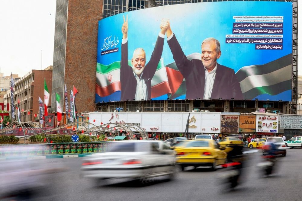 Des véhicules passent devant une affiche représentant le président iranien Massoud Pezeshkian (à droite) et le chef du Hamas palestinien Ismail Haniyeh à Téhéran, le 12 août 2024.