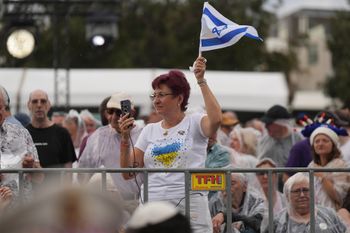 An attendee waves Israel's flag at Bondi Beach before a ceremony to mark the National Day of Reflection for victims and survivors in Sydney, Sunday, Dec. 21, 2025