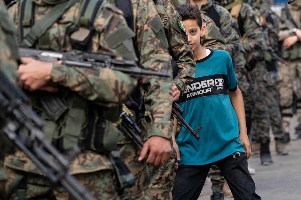 AP Photo/John Minchillo A child weaves between columns of Hamas terrorists as they parade through the streets in Gaza City, May 22, 2021.