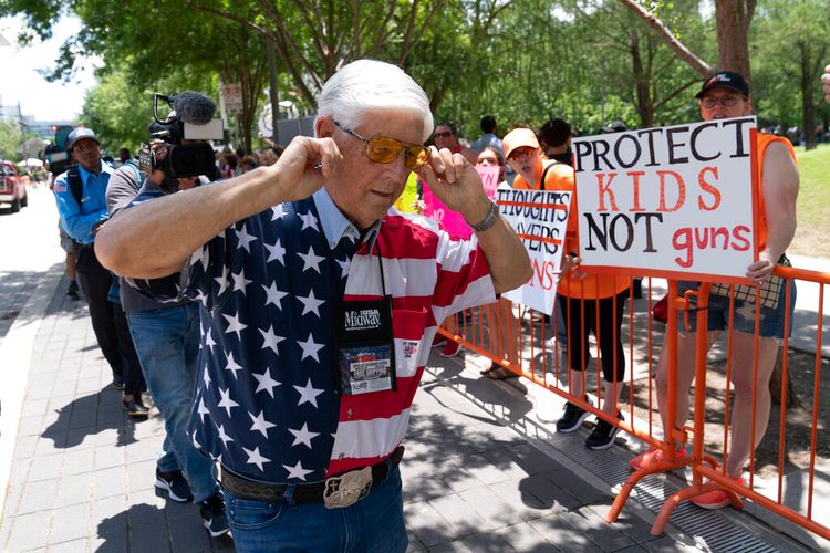 A member of the National Rifle Association walks past protesters in Texas, the United States, on May 27, 2022.