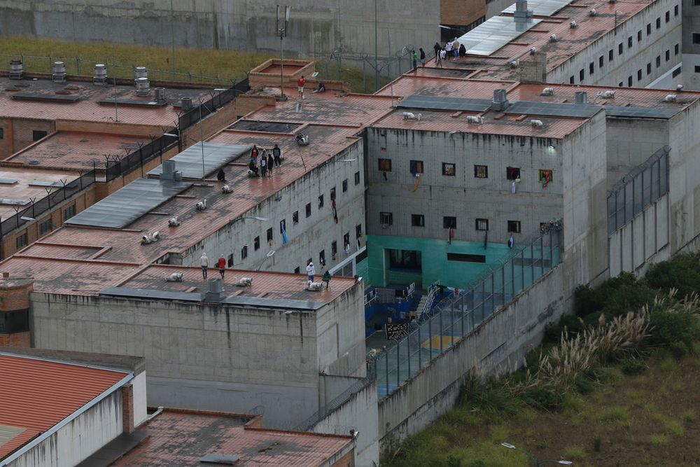 FILE PHOTO. Prisoners stand on the roof of the Turi jail where dozens of prison guards and police officers have been kidnapped by the inmates, in Cuenca, Ecuador.