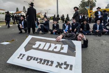 Ultra orthodox Jews block a road during a protest against the ultra-Orthodox draft bill, with the sign saying they would rather die than jointhe military