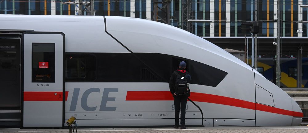 An employee of German railway operator Deutsche Bahn (DB) stands next to an ICE high speed train at the main railway station in Munich, southern Germany, on August 23, 2021.