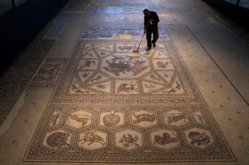 A worker cleans a restored Roman-era mosaic ahead of its display in its hometown at the inauguration of the Shelby White & Leon Levy Lod Mosaic Archaeological Center, in Lod, central Israel, June 23, 2022.