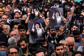 People hold up posters of President Ebrahim Raisi during a mourning ceremony for him at Vali-e-Asr square in downtown Tehran, Iran, Monday, May 20, 2024.