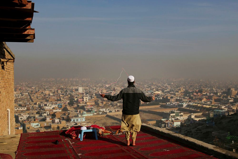 An Afghan boy skips on the rooftop of an Islamic seminary overlooking the Kabul skyline in Afghanistan, on December 8, 2019.