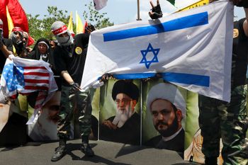 A demonstrator, covering his face in the style of Palestinian militants, holds a representation of the Israeli flag which is set on fire during the annual Quds Day in Tehran, Iran.