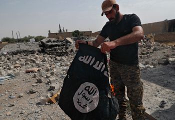 Illustration - un membre de la milice chrétienne syriaque qui combat des militants du groupe État islamique brûle un drapeau de l'EI sur la ligne de front du côté ouest de Raqqa, le 17 juillet 2017