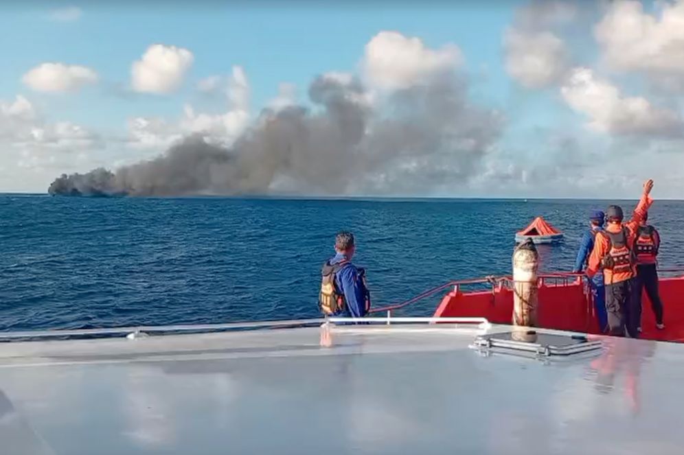 En esta imagen tomada de un video de la Agencia Nacional de Indonesia de Búsqueda y Rescate (BASARNAS), la tripulación de una embarcación de rescate observa una columna de humo después de que un ferry de pasajeros se incendió después de partir de la isla de Bali hacia la isla de Lombok, el miércoles 12 de agosto de 2026, en el estrecho de Lombok, Indonesia 