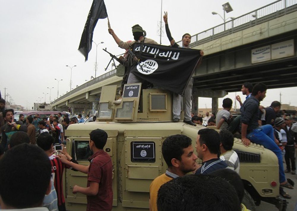 Islamic State fighters hold up their flag west of Baghdad, Iraq - March 30, 2014
