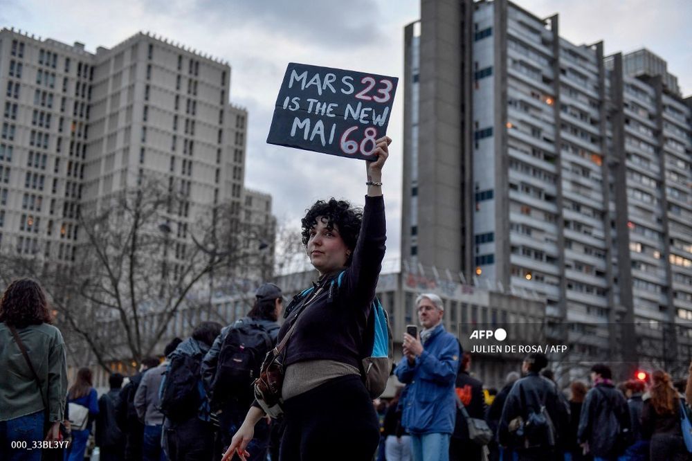 Une manifestante tient une pancarte lors d'une manifestation contre la réforme des retraites sur la Place d'Italie à Paris, le 18 mars 2023