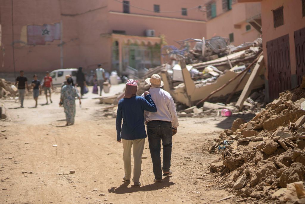 أشخاص يسيرون وسط الأضرار التي لحقت بالزلزال في بلدة أمزميز، بالقرب من مراكش، المغرب