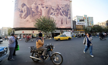 Des passants défilent devant une grande banderole représentant des membres de la Royal Navy britannique capturés par le Corps des gardiens de la révolution iranienne au cours des années précédentes, place Enghelab (Révolution) à Téhéran, la capitale, le 11 novembre 2025. 