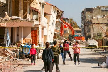 Children play with a ball next to destroyed buildings in Samandag, southern Turkey.