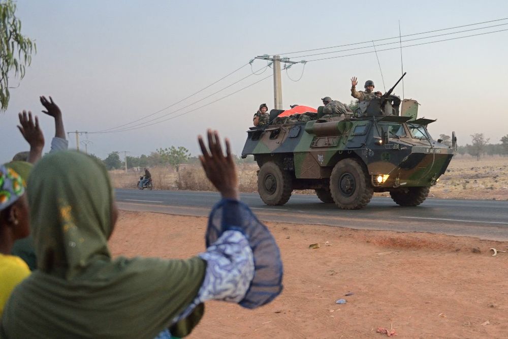 This file photo taken on January 15, 2013 shows Malian people waving to French soldiers as a convoy of armored vehicles leave Bamako and start a deployment to the north of Mali as part of the "Serval" operations.